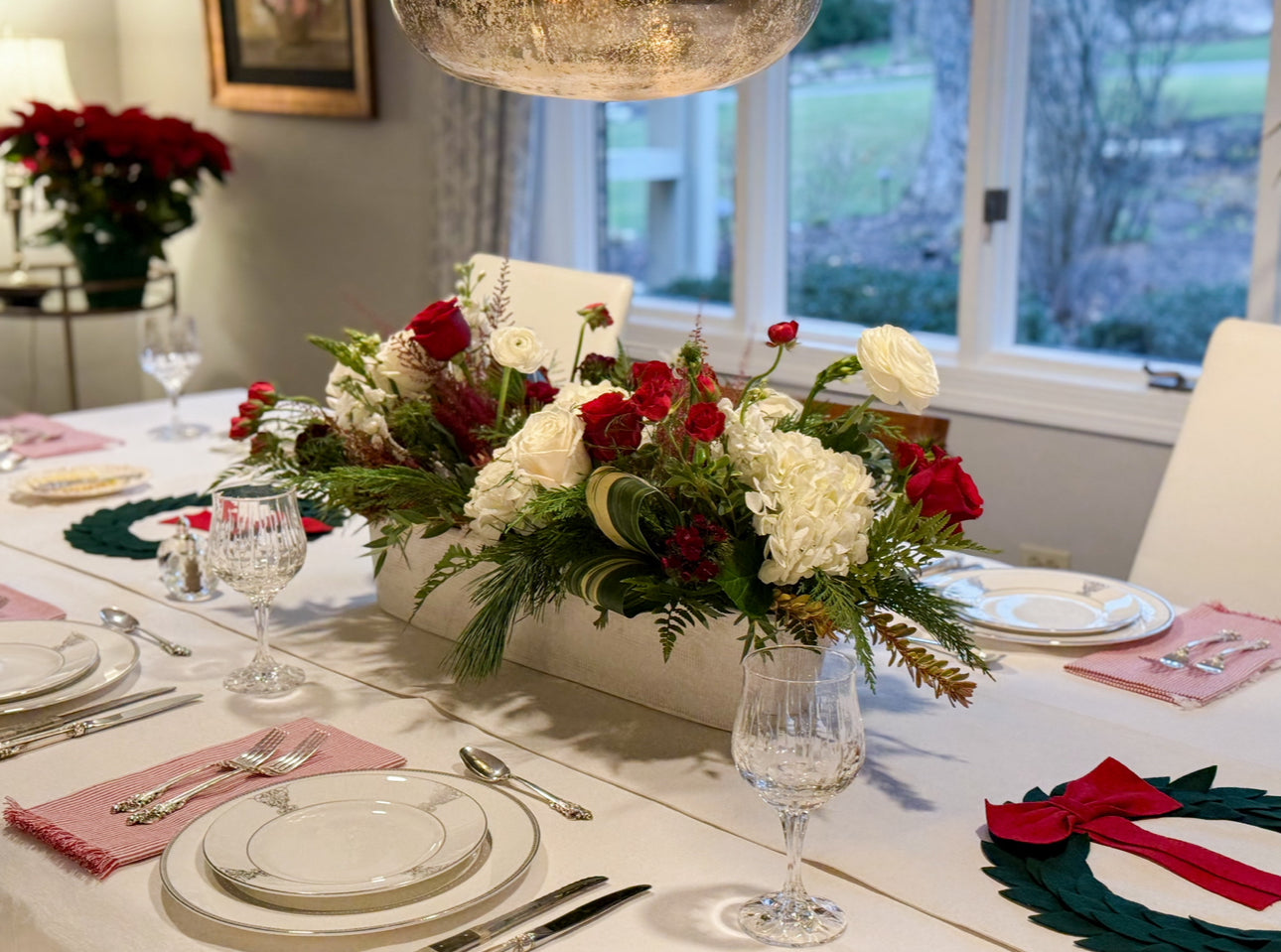 Decorative floral arrangement on a table with place settings and glasses.